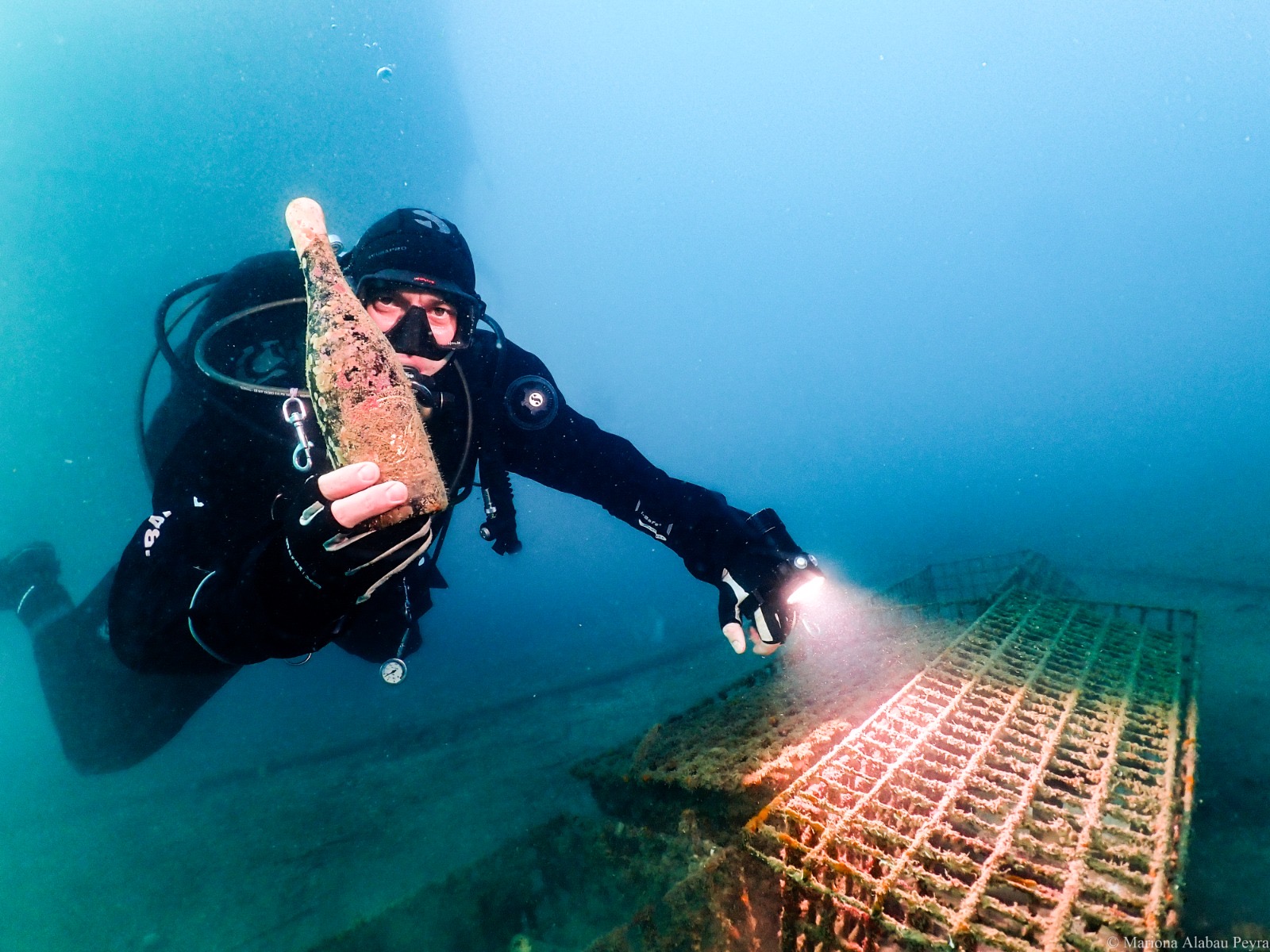 Buceador rescatando una botella de vino envejecida bajo el mar de la Costa Brava